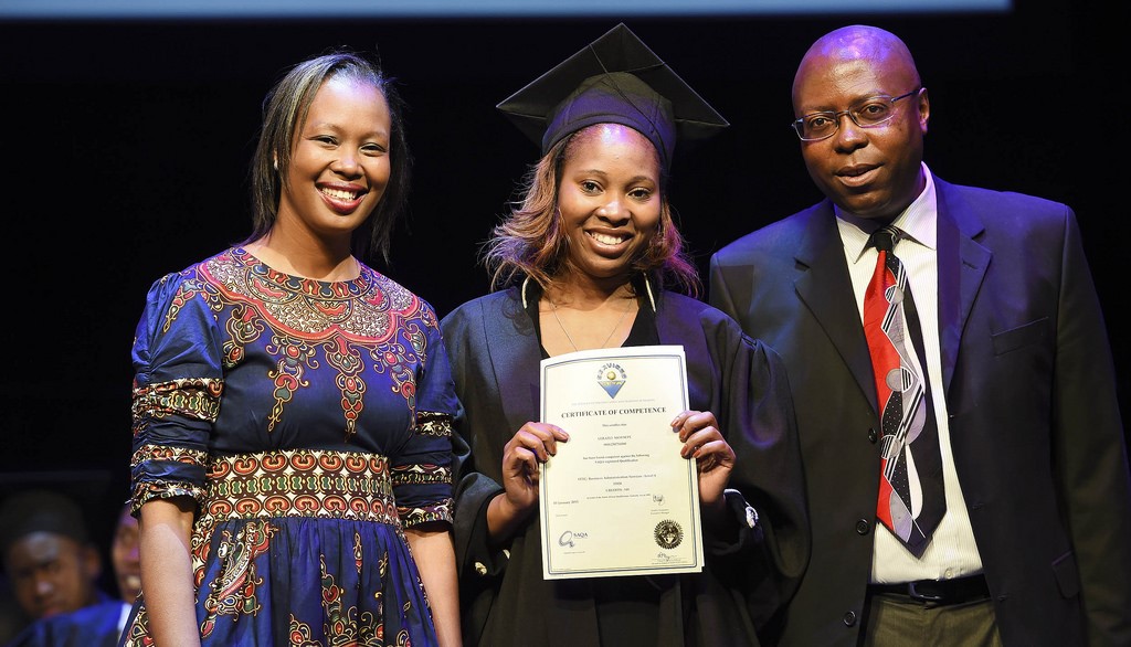 Graduate holding a certificate with Limco representatives on stage.